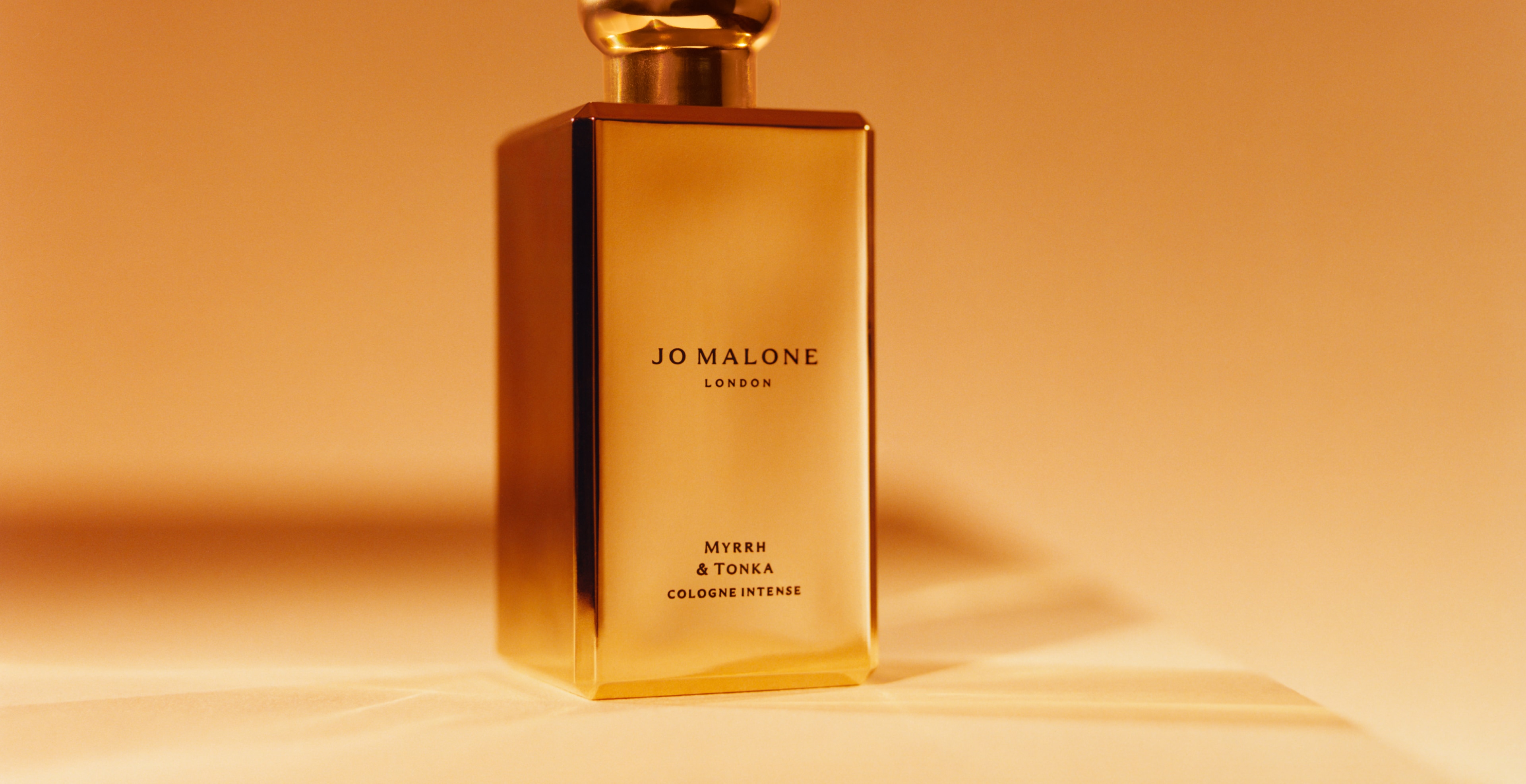 Jo Malone London myrrh & tonka in a gold bottle with gold backdrop