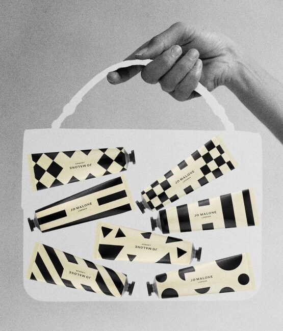 Black, white & cream image of a transparent, medium bag held by a hand, containing seven patterned hand creams in tubes.