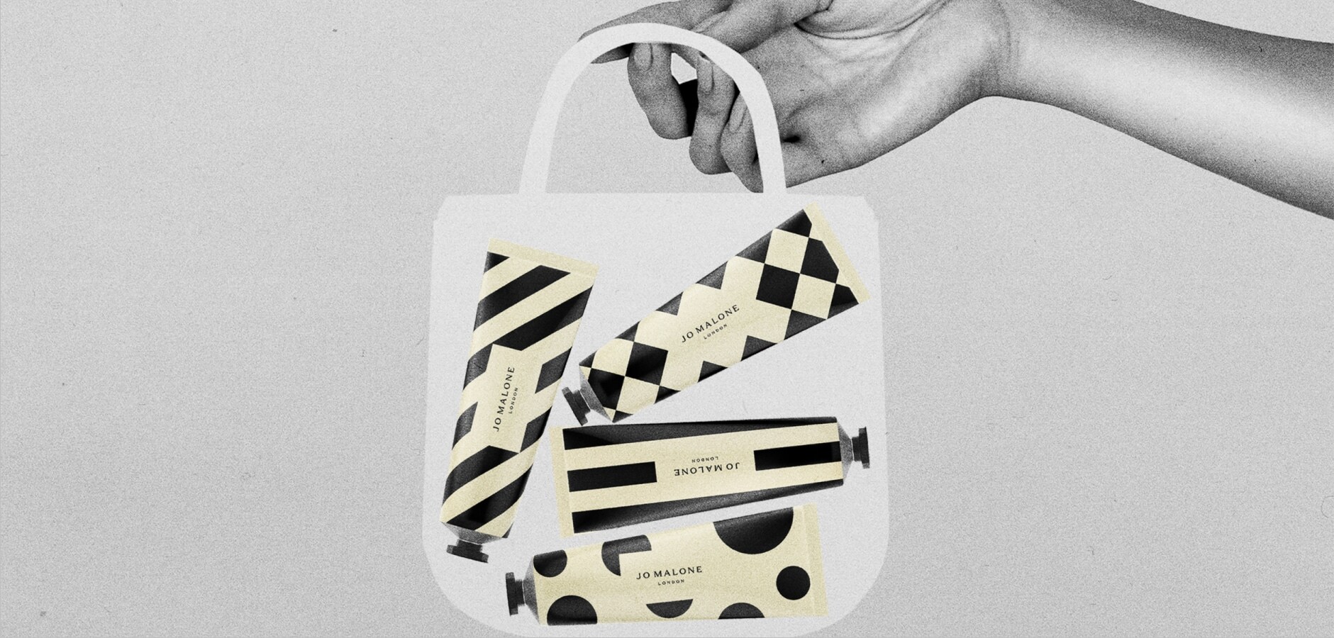 Black, white & cream image of a transparent, medium bag held by a hand, containing seven patterned hand creams in tubes.