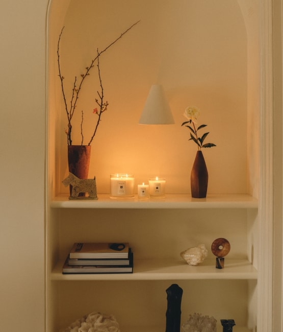 Jo Malone London candles on shelves with ornaments books and vases