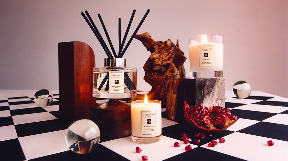 Jo Malone London Candles & Diffuser surrounded by wood and pomegranates
