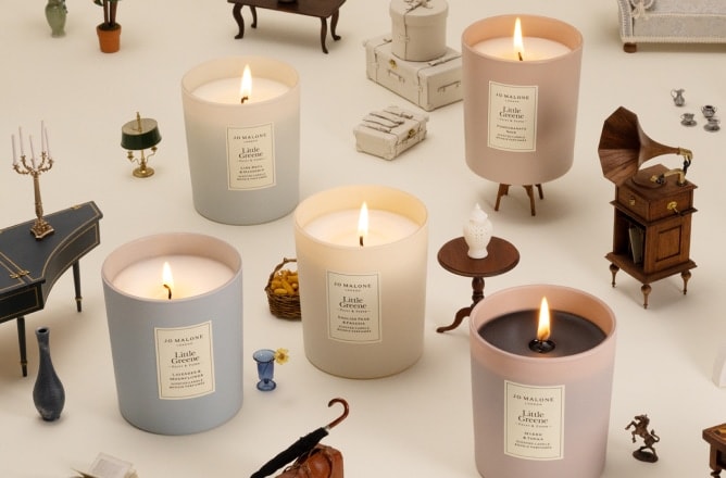 Jo Malone London cologne on a marmalade jar with an orange, styled on a red gingham tablecloth in a playful setup.