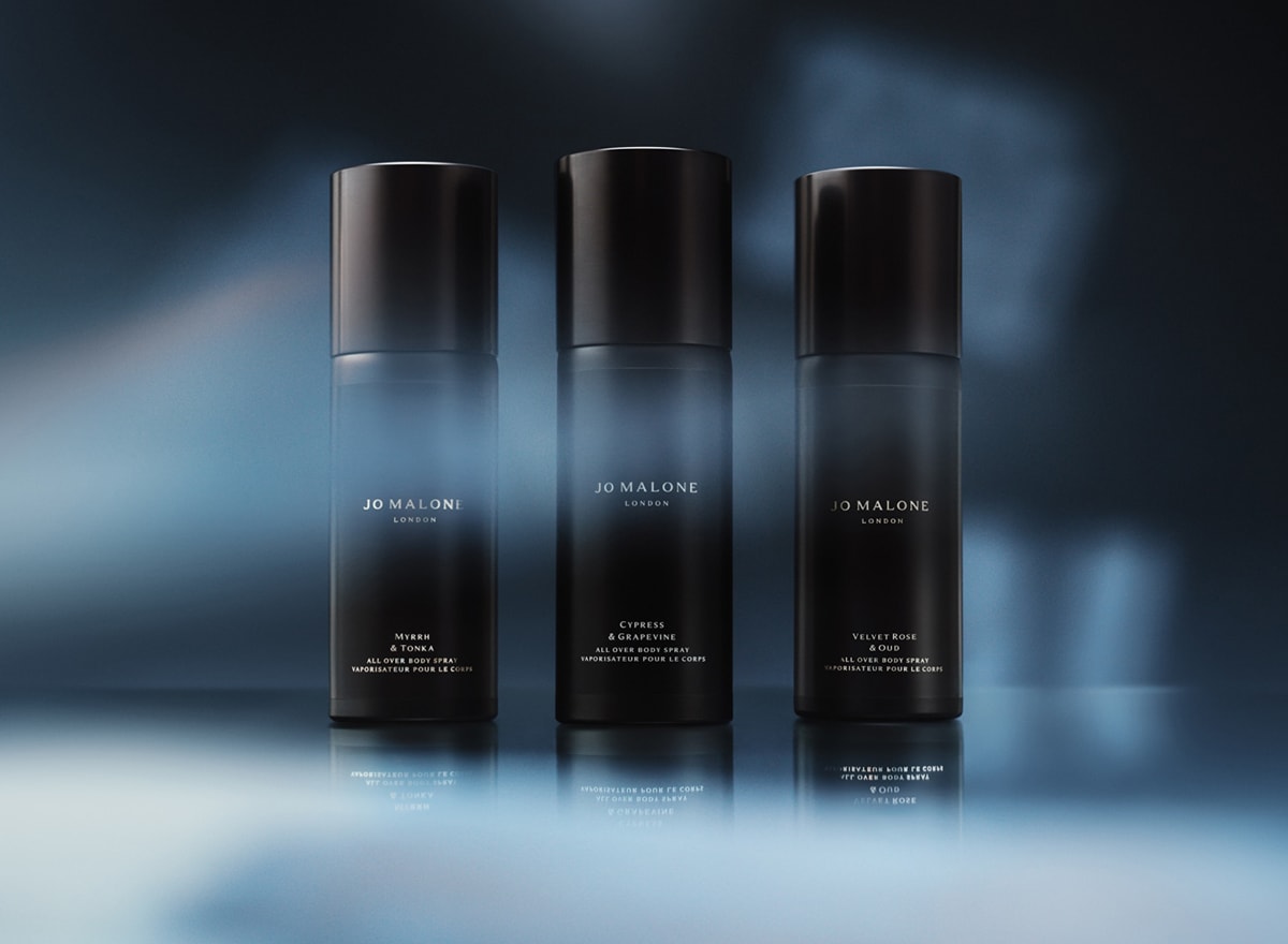 Three black Jo Malone London body spray bottles with blue light and shadows in the background.