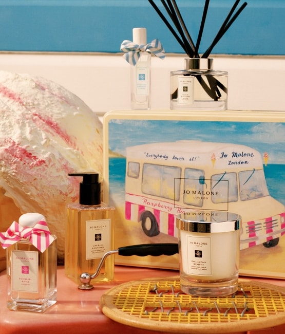 A variety of Jo Malone London products sit amongst a sports racquet and a tin box with an icecream van on the front.