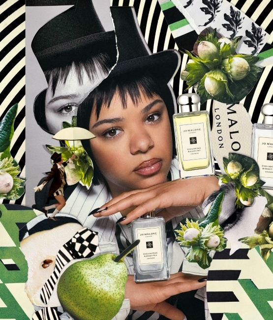 Person with Jo Malone London bottles, pears, and flowers on a black-and-white striped background.