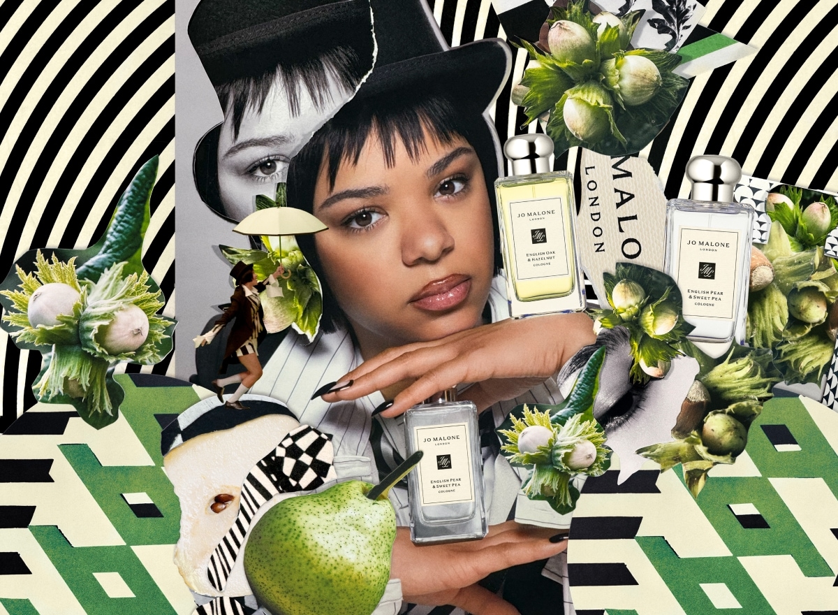 A person in a top hat sprays themselves with perfume, surrounded by a Jo Malone London display with black and white print.