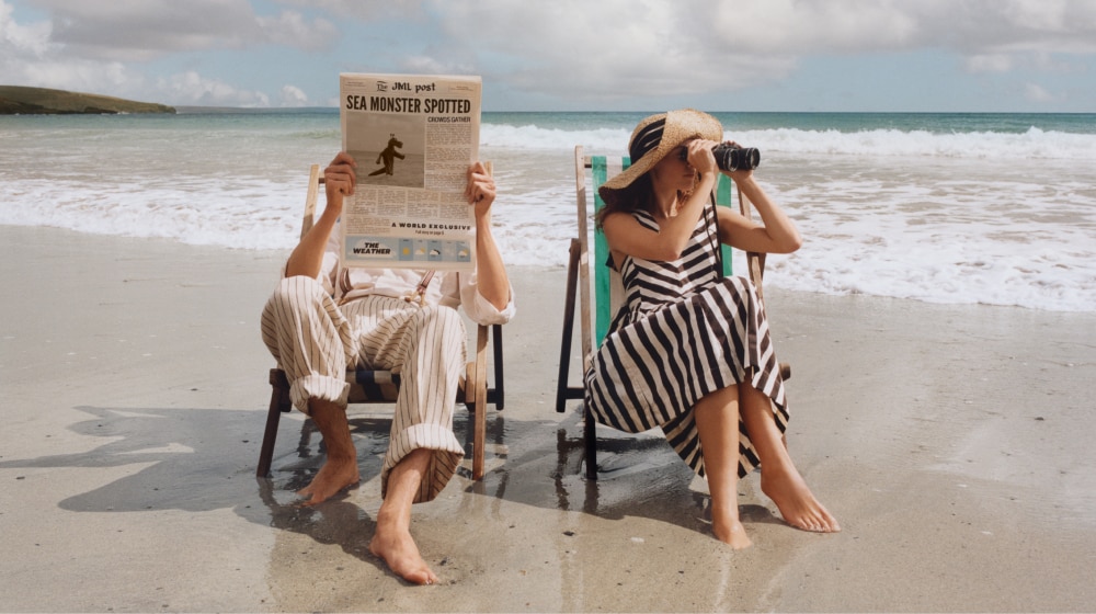 Jo Malone London | Man and Women in deck chair on the beach with giant cologne bottle in front of them 