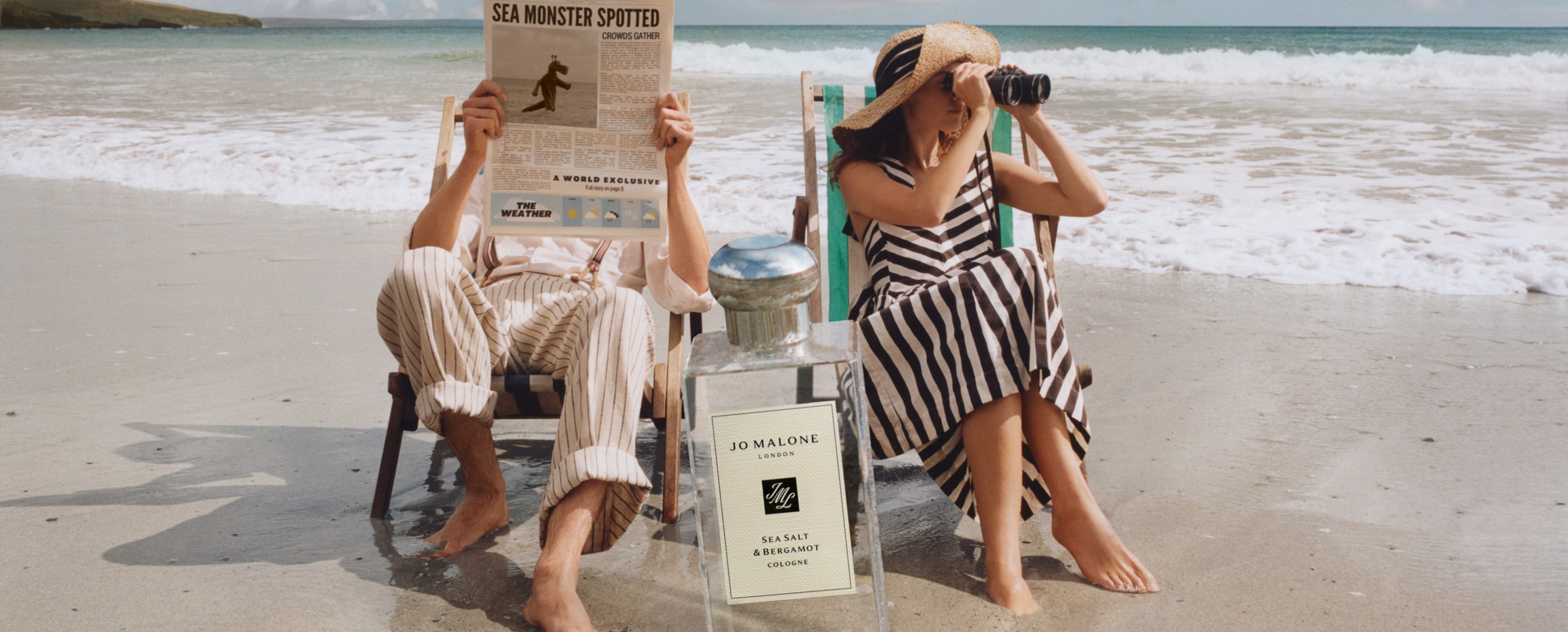 Jo Malone London | Man and Woman Sitting on deck chair at the beach with massive cologne in front of them 