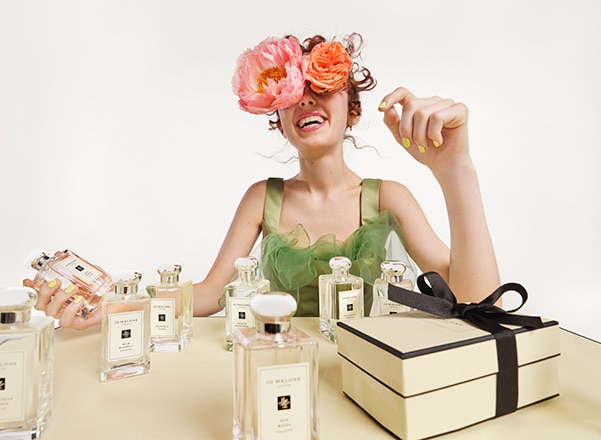 Jo Malone London asset featuring a colognes alongside jo malone gift boxes on a table with a person sitting behind them