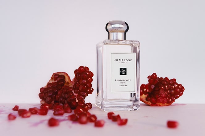 Jo Malone London Pomegranate Noir cologne with pink floral print on the sides, against white background.