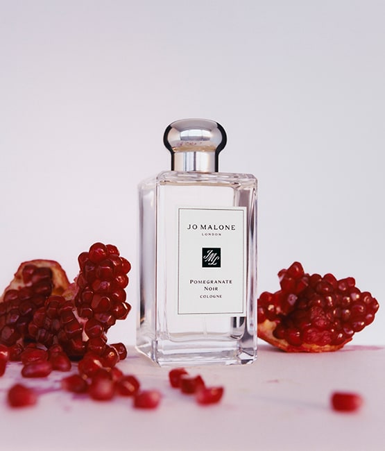 Pomegranate Noir Cologne surrounded by pomegranates