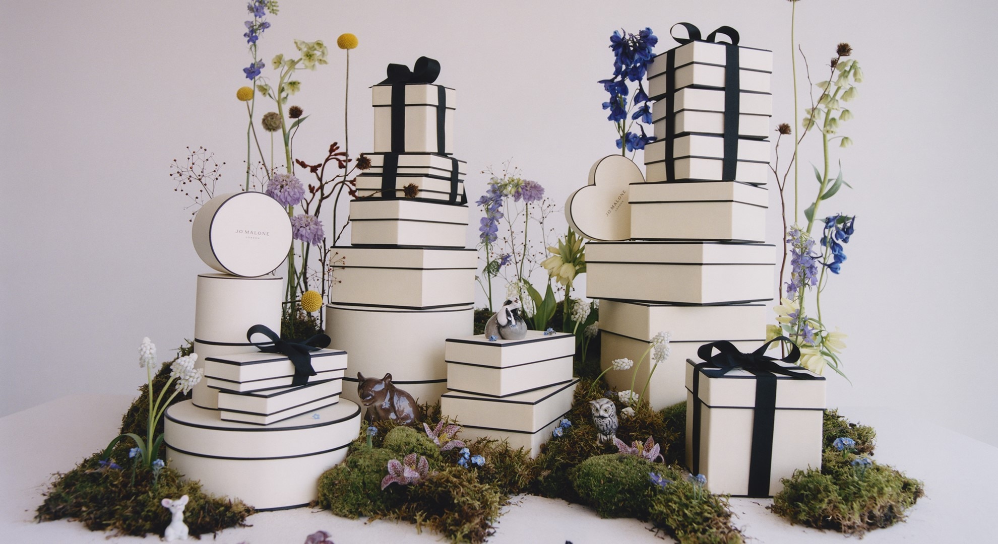 Jo Malone London Gift Boxes stacked up, surrounded by greenery and flowers