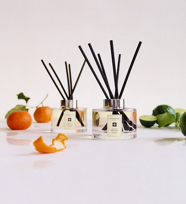 Jo Malone London lime basil and mandarin diffuser surrounded with mandarins and limes