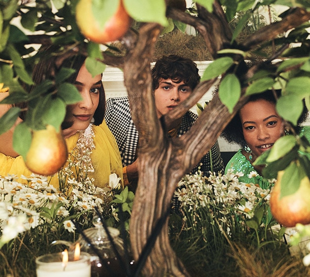 image of three people peeking through a pear tree